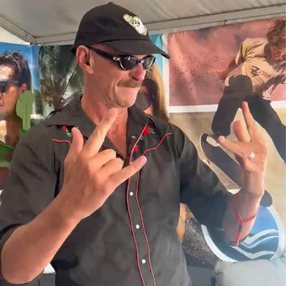 Man making a hand gesture in front of a colorful background with people.